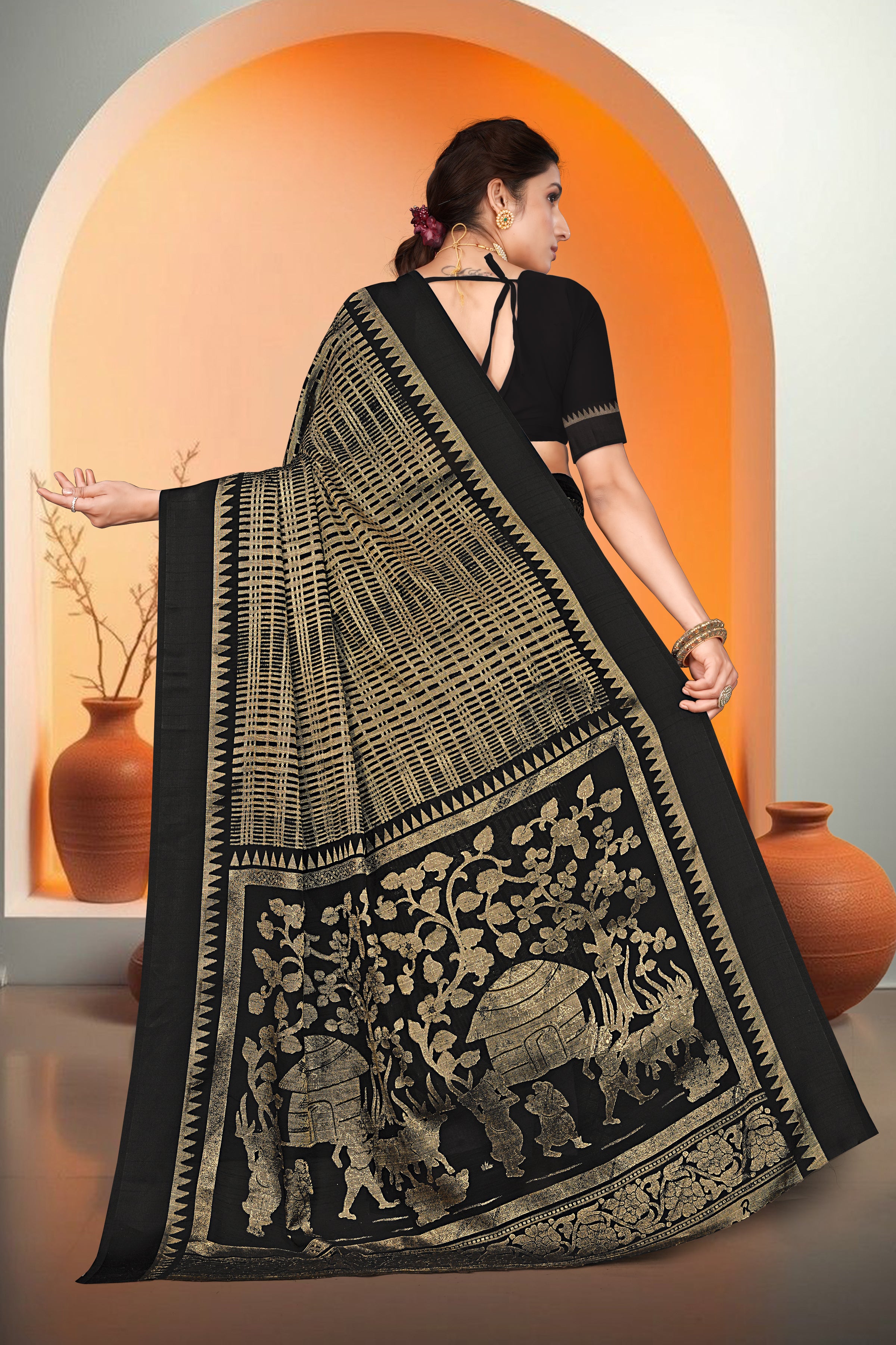 Woman wearing a black saree with gold patterns in an orange and white setting